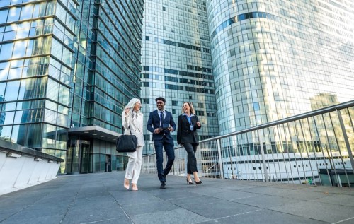Diverse business professionals walking, communicating, and laughing while moving together in a