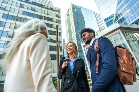 Diverse business professionals in smart casual attire chat and walk outside in a modern financial