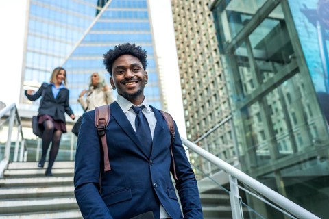 African american businessman smiling at camera and walking up stairs in a modern urban environment