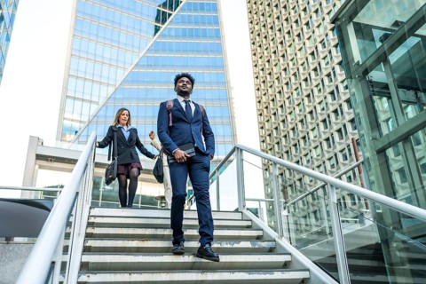 Diverse business people walking on stairs in a contemporary urban environment with tall, geometric