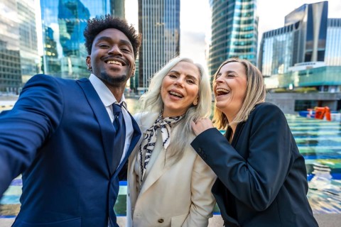 Diverse business professionals feeling happy and celebrating success while taking a selfie