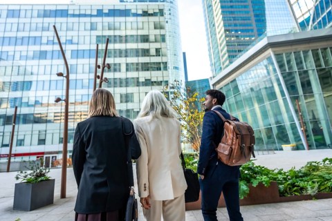 Diverse group of business people walking through a modern urban city district, discussing future