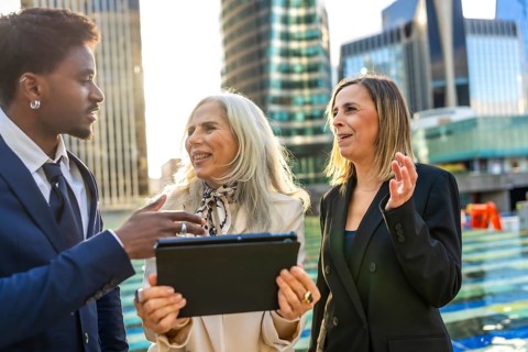 Diverse business team engaging in an informal outdoor meeting, discussing a project while looking