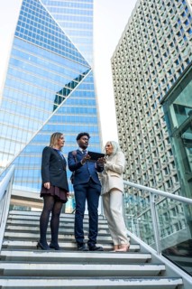 Diverse business team meeting on outdoor stairs in a downtown corporate district, collaborating