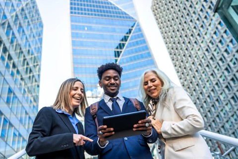 Diverse business people smiling and showing teamwork, standing outdoors in a corporate city