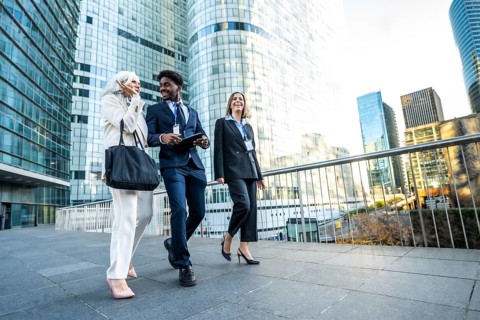Diverse business professionals senior woman, black man, and young woman walk through a modern