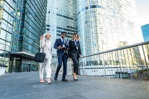 Diverse business professionals, including a senior woman, walking together on an urban walkway