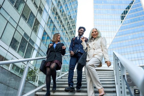 Diverse group of business professionals walking down outdoor stairs in a modern financial district,