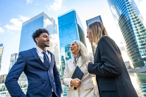 Diverse business professionals networking and discussing projects outdoors in front of modern