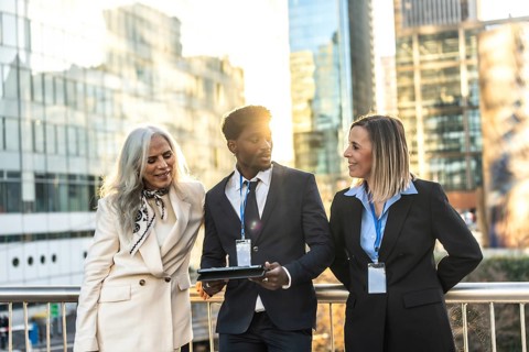 Diverse group of business people collaborating and discussing work in an urban setting, featuring