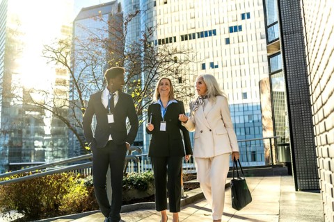 Diverse business professionals walking outdoors on a sunny day, engaging in conversation while