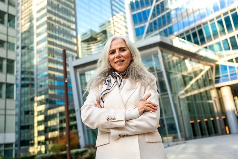 Senior businesswoman with gray hair and a formal elegant blazer standing outdoors with folded arms,
