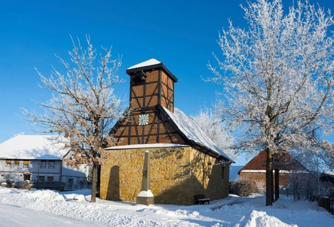 Snowy half-timbered church with blue sky and snow-covered trees in the background, Old Chapel, 15th