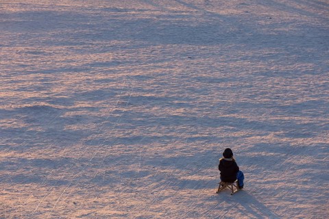 A child sits alone on a sled on Tempelhofer Feld in Berlin on 11.01.2026