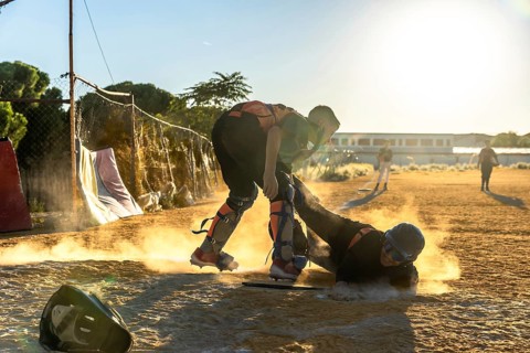 Baseball player slides into home plate at sunset, kicking up dust as catcher crouches ready for a