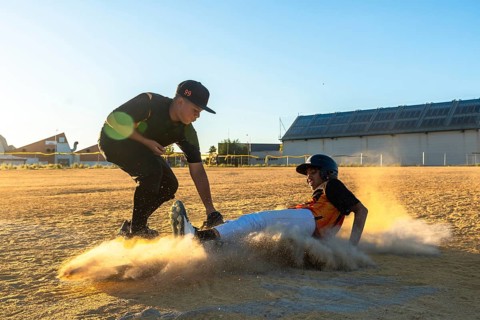 Two young baseball players engaged in a competitive game, one player sliding into base creating a