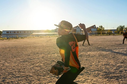 Young baseball player wearing a cap and jersey, preparing to throw the ball during a game on a