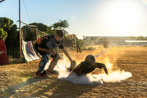 Young baseball player slides into base, sending up a cloud of dust as catcher waits on the dirt
