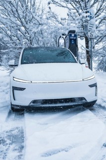 White electric car charging at a charging station in a snowy winter landscape, Tesla Model Y
