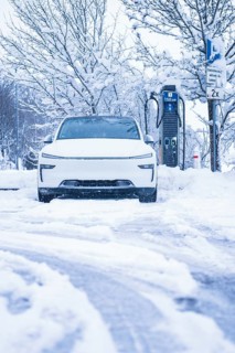 An electric car is parked on a snowy road next to a charging station, Tesla Model Y electric car,