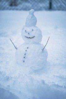 A humorous snowman with twig arms and button-like smile in the snow, Waldachtal, Freudenstadt