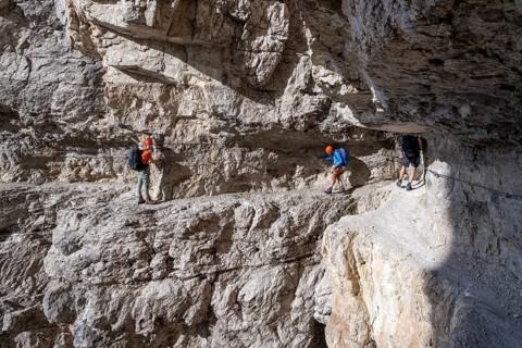 Mountaineers on an exposed rock band in the secured via ferrata Bocciere Centrale, Brenta