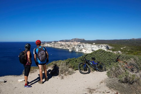 Cyclists look at the ville haute or upper town or medieval old town of Bonifacio, Corse-du-Sud
