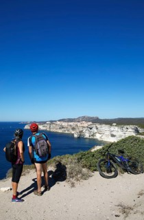 Cyclists look at the ville haute or upper town or medieval old town of Bonifacio, Corse-du-Sud