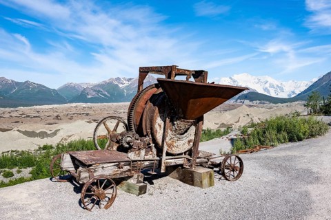 Old rusted moving mill for rock in front of mountain landscape with Kennicott Glacier, Historic
