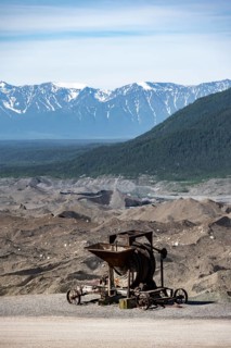 Old rusted moving mill for rock in front of mountain landscape with Kennicott Glacier, Historic