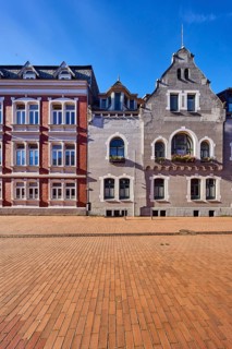 Historic residential buildings, façade with windows, gables and tail gables, paving street, blue