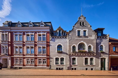 Historic residential buildings, façade with windows, gables and tail gables, paving street, blue