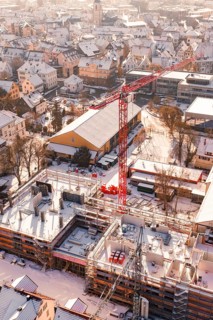 Snowy town with a construction site and a distinctive red crane, Zellerschule building, Nagold,