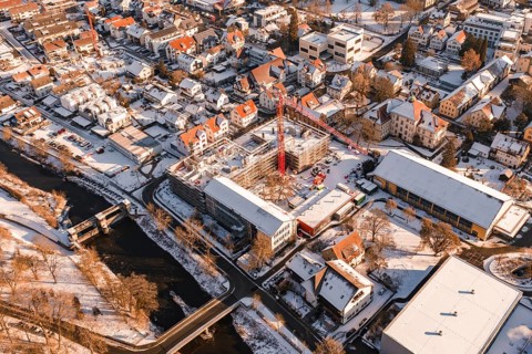 Snowy town with a red construction crane on a construction site and a river, Neubau Zellerschule,