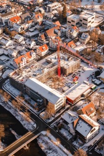 Construction site in a snowy urban area with a visible red construction crane, Zellerschule