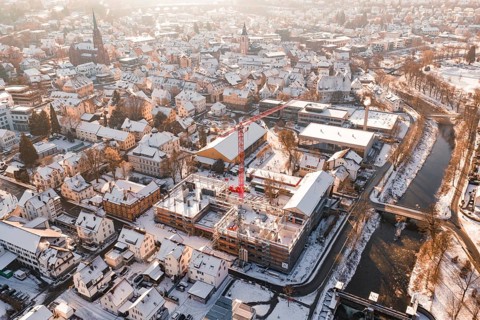 City in winter with an active construction site and visible church roof in the background,