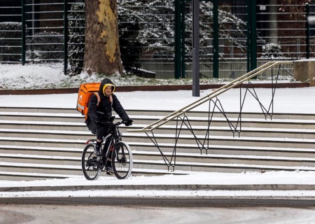 Winter in Stuttgart. There is a closed blanket of snow in the city center. Lieferando cyclists in