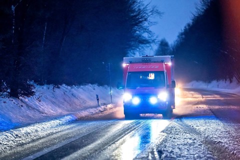 Ambulance during an alarm trip, with flashing lights, in winter, slush, slippery roads, country