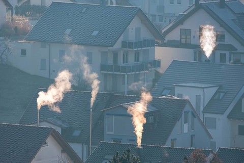 Sunrise over a village with smoking chimneys, calming morning atmosphere, symbolic image,