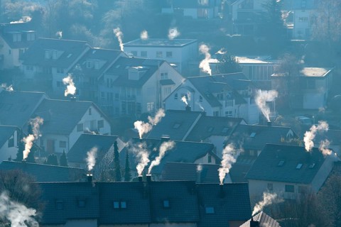 Cold winter morning view of a settlement with numerous smoking chimneys, symbolic image,