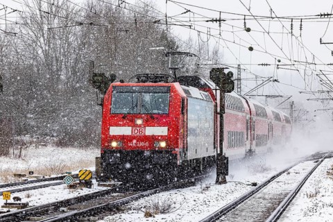 RegionalExpress RE on the road through a winter landscape in snowfall. A train on the line in the