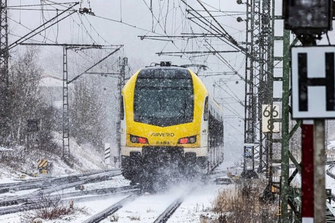 Regional train from Arverio on its way through a winter landscape in snowfall. The railcar train is