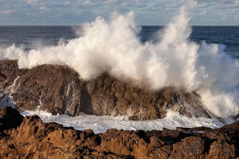 Powerful ocean swells hitting rocks at the mainland's eastern point. Crashing waves, Byron Bay, New
