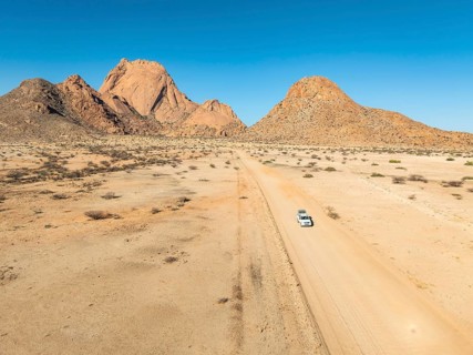 Aerial view, car on sandy road, mountains in the desert, Spitzkoppe summit, Namib desert, Namibia