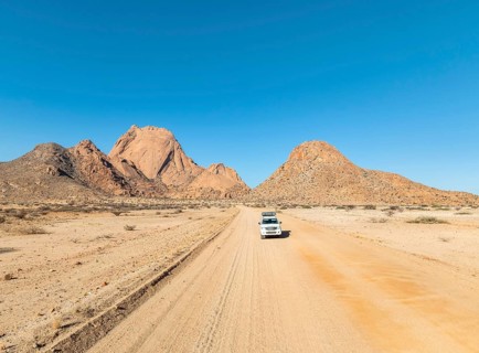 Car on sandy road, mountains in the desert, Spitzkoppe summit, Namib desert, Namibia