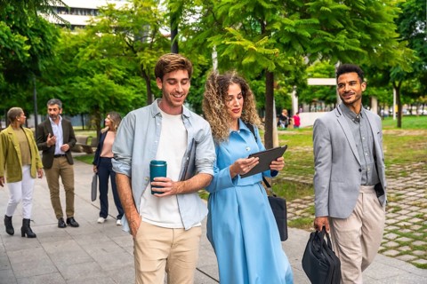 Group of diverse business professionals and entrepreneurs walking along a paved path in a green