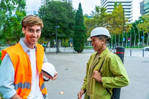Diverse team of architects and engineers smiling and talking while standing outdoors in the city,