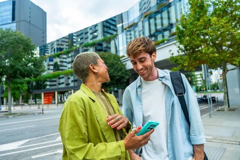 Two diverse colleagues enjoying a casual conversation and sharing a smartphone screen on an urban