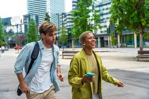 Diverse business colleagues walking actively outdoors in a modern urban environment, sharing a