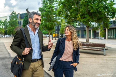Professional man and woman walking outdoors in a modern urban environment, having a conversation